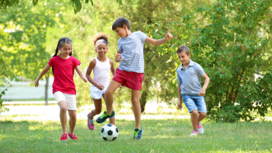 Small group of kids kicking a soccer ball around in a park